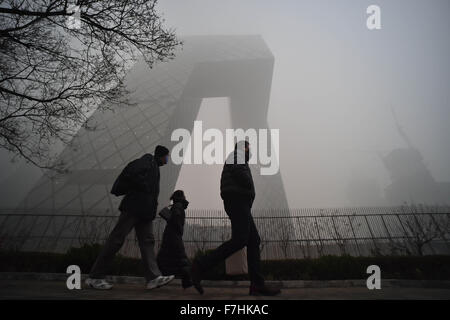 Beijing, China. 1st Dec, 2015. People wearing respirators walk past the China Central Television (CCTV) headquarters in Beijing, capital of China, Dec. 1, 2015. Heavy fog hit Beijing on Tuesday. Credit:  Luo Xiaoguang/Xinhua/Alamy Live News Stock Photo