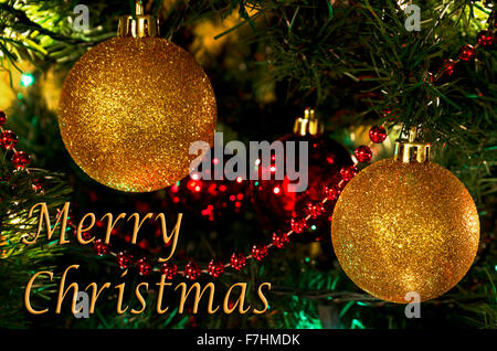 Sparkling gold ball ornaments on a Christmas tree with a Merry Christmas greeting. Stock Photo