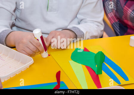child hands glue colored paper on application master class Stock Photo