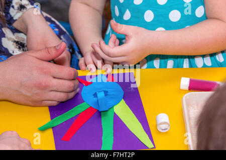 children and adults hands glue colored paper on application master class Stock Photo