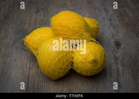 Fresh citrus in mesh bag on beige background. Lemons and limes in