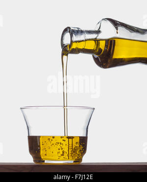 Extra virgin olive oil being poured from a bottle into a glass. Stock Photo