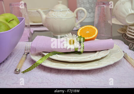 Porcelain plates and pot on table with violet mats set for breakfast Stock Photo