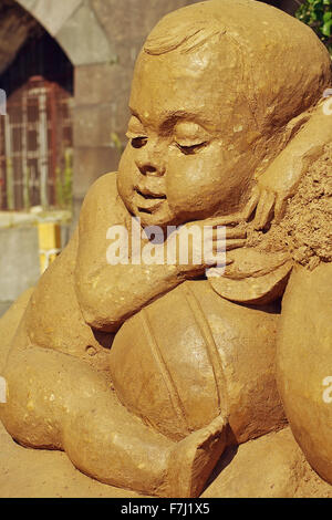 Sand Sculpture Festival 'Treasure Island' in Saint - Petersburg, August 3, 2014.Sculpture of a small child a seated among toys. Stock Photo