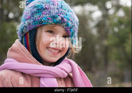 Little girl wearing knit hat and scarf, smiling, portrait Stock Photo