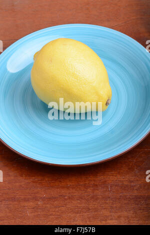Whole lemon on a blue plate on wooden background Stock Photo