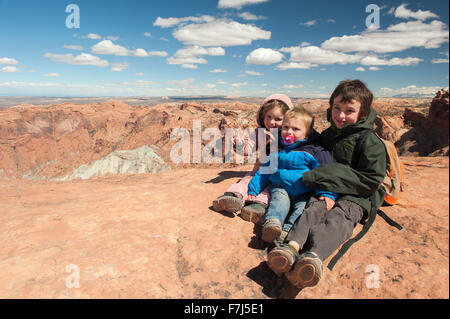 Children sitting at edge of canyon in Canyonlands National Park, Utah, USA Stock Photo