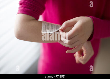 Child applying temporary tattoo to arm, cropped Stock Photo