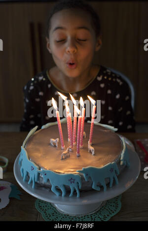 Girl blowing out candles on birthday cake Stock Photo