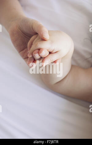 Child's hand holding baby's hand Stock Photo