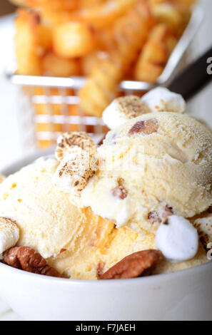 Bowl of Butter Pecan Ice Cream with whole pecans and toasted marshmallows with crispy French Fries Stock Photo