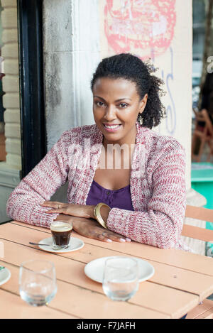 Woman sitting at sidewalk cafe Stock Photo