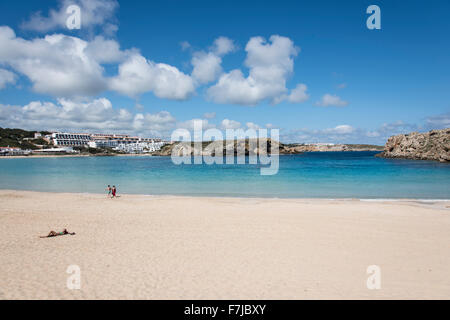 The sandy beach and beautiful blue waters of the bay make Arenal d’en Castell a lovely spot to sunbathe. Stock Photo