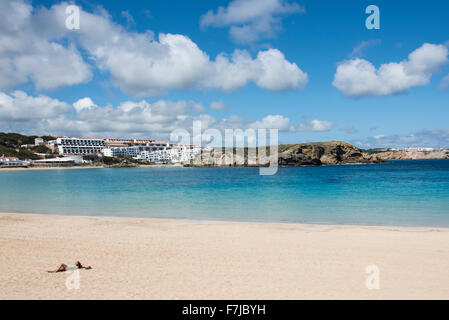 The sandy beach and beautiful blue waters of the bay make Arenal d’en Castell a lovely spot to sunbathe. Stock Photo