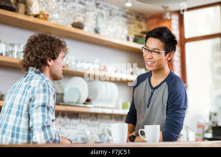 Two young handsome men drinking tea and talking in cafe Stock Photo