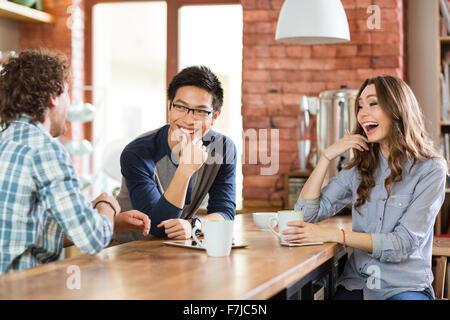 Happy positive friends drinking tea and laughing in cafe Stock Photo