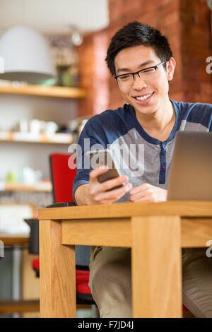 Happy smiling asian student using laptop and cellphone sitting in cafe Stock Photo