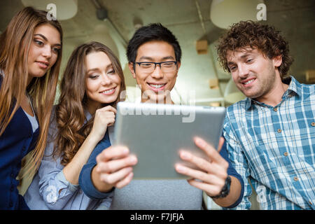 Group of positive cheerful happy friends using tablet Stock Photo