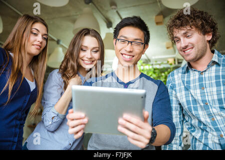 Happy positive attractive people looking on the screen of tablet and smiling Stock Photo