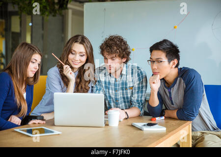Group of concentrated smart students sitting in classroom and using laptop together Stock Photo