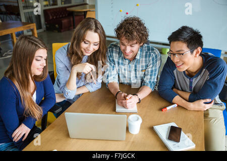 Group of positive confident managers discussing presentation of new project and using laptop in office Stock Photo