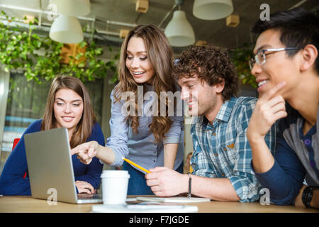 Group of enthusiastic cheerful colleagues discussing ideas and planning work in office Stock Photo