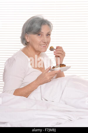 Older woman in bedroom with cake Stock Photo