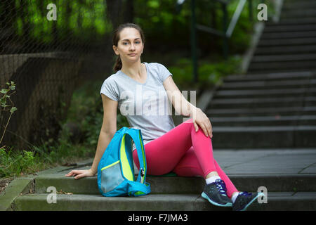 Young sporty girl sitting on the steps outdoors.