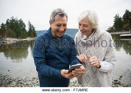 Senior couple using cell phone at lake