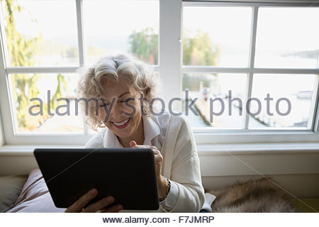 Smiling senior woman using digital tablet at window