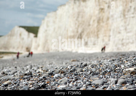 Low level quirky camera angle of beach pebbles and stones with blurred chalk cliffs along the coast of Birling Gap East Sussex Stock Photo