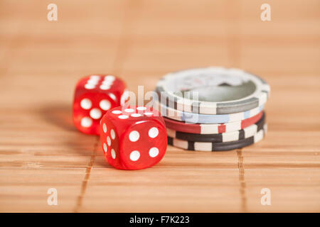 two red dices and gambling chips on wooden background Stock Photo