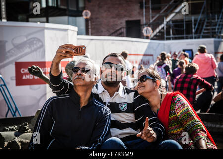 Family having fun wearing sunglasses & waving to a camera taking selfie Stock Photo