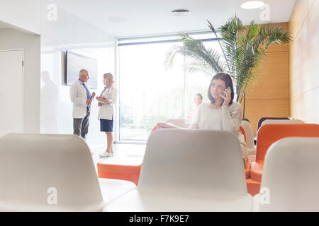 Woman talking on cell phone in hospital lobby Stock Photo