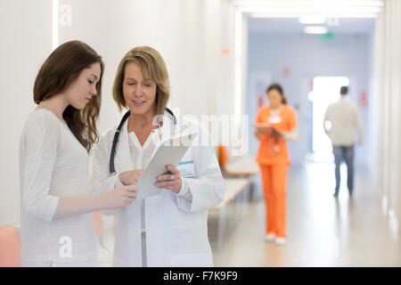 Doctor and patient reviewing medical record in hospital corridor Stock Photo