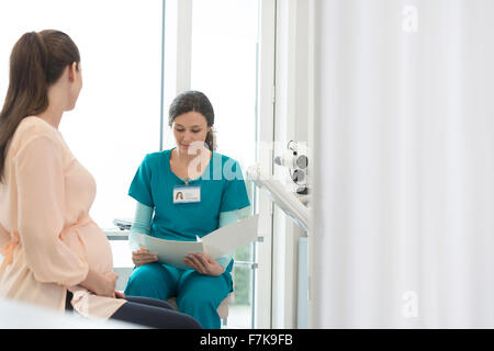 Nurse and pregnant patient reviewing medical chart in examination room Stock Photo