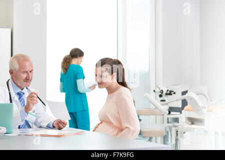 Doctor and pregnant patient discussing prescription in clinic Stock Photo