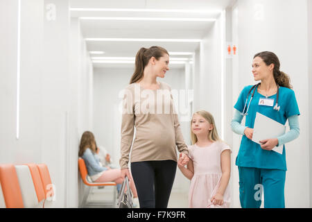 Nurse talking to mother and daughter in hospital corridor Stock Photo