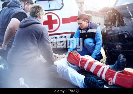 Rescue workers tending to car accident victim in road Stock Photo