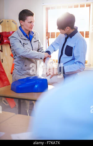 Instructor guiding student with manual resuscitator in CPR training class Stock Photo