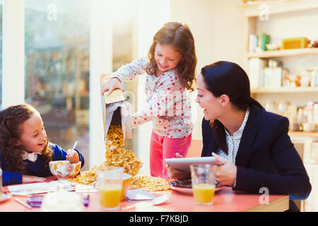 Girl pouring abundance of cereal at breakfast table Stock Photo