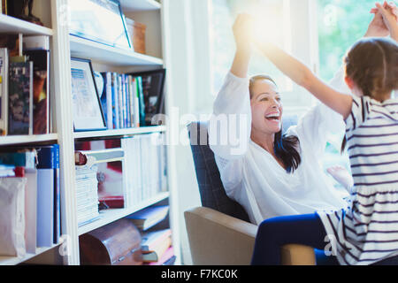 Enthusiastic mother and daughter holding hands overhead Stock Photo