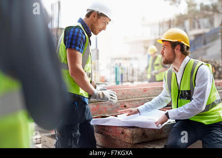 Construction worker and engineer reviewing blueprints at construction site Stock Photo