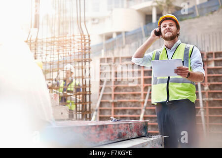 Engineer with digital tablet talking on cell phone at construction site Stock Photo