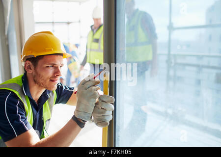 Construction worker measuring window at construction site Stock Photo