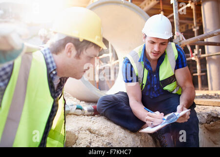 Construction workers with clipboard talking at construction site Stock Photo