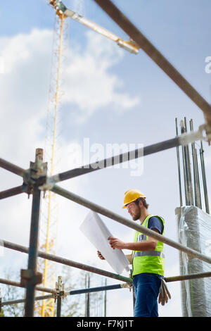 Engineer reviewing blueprints at high rise construction site Stock Photo