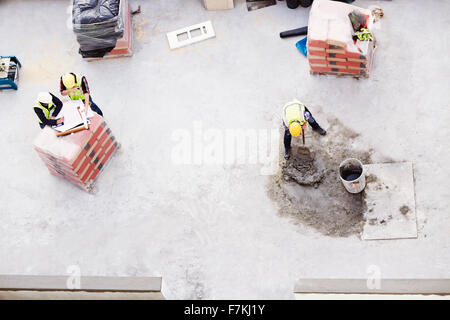 Overhead view of construction workers laying concrete at construction site Stock Photo