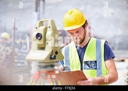 Engineer with clipboard behind theodolite at construction site Stock Photo