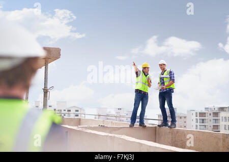 Construction worker and engineer talking at highrise construction site Stock Photo